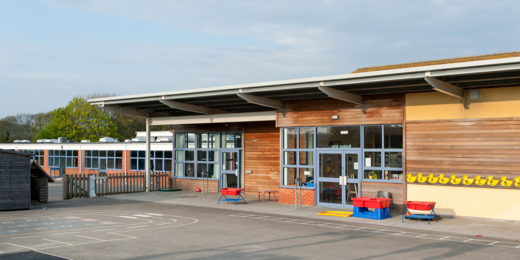 Exterior view of a primary school building with children playing outside, showcasing a safe and welcoming learning environment.