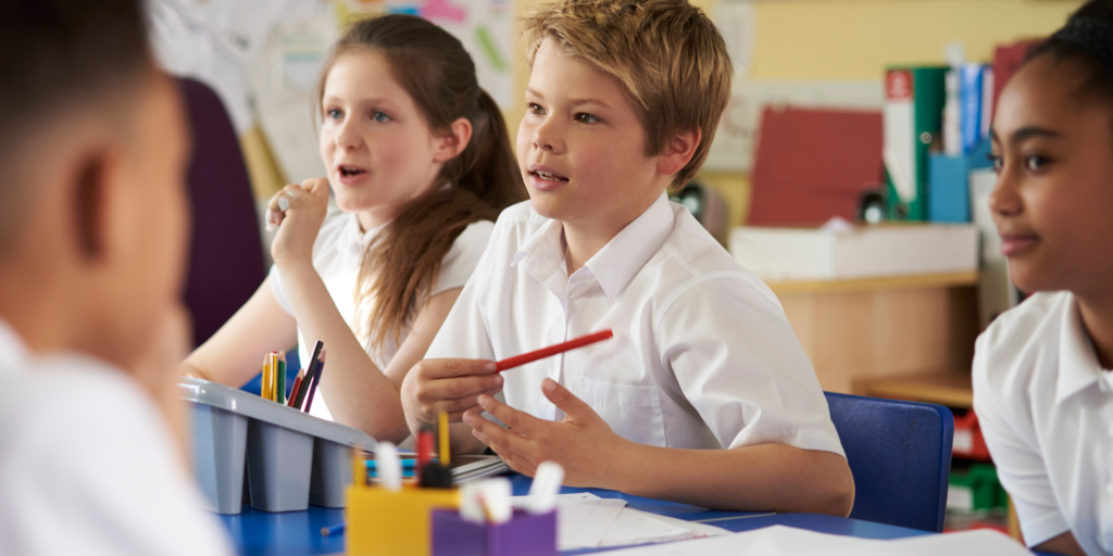 "Children in a classroom holding pencils, engaged in learning activities."